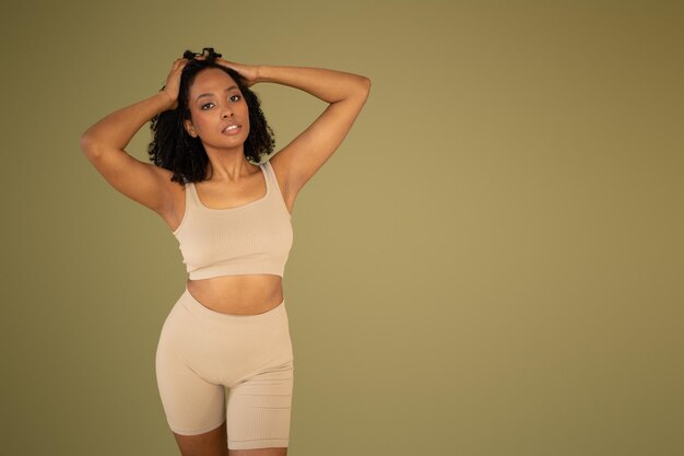 A woman posing confidently in a beige ribbed crop top and matching shorts set.